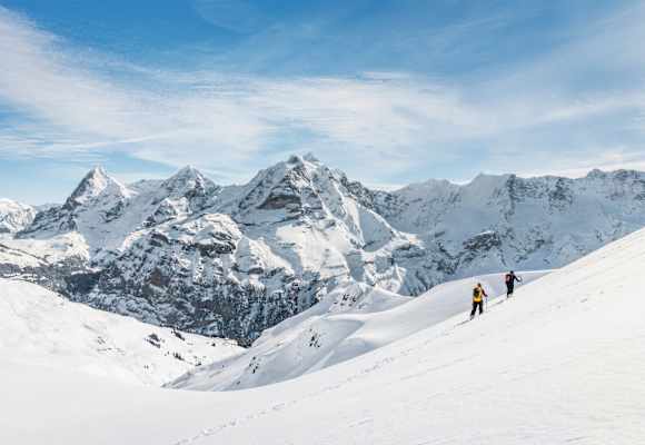 Zwei Schneeschuhwanderer vor atemberaubendem Bergpanorama.