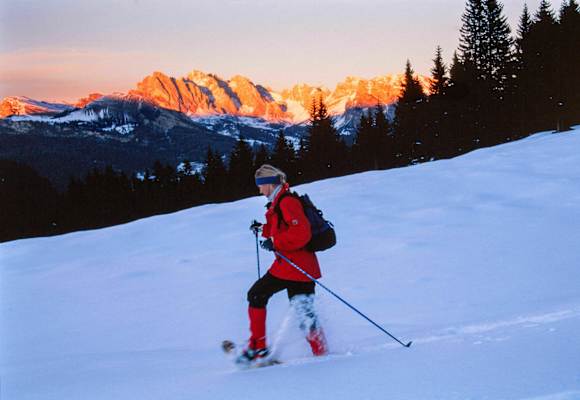 Alpenglühen: Schneeschuhwanderin vor Bergpanorama