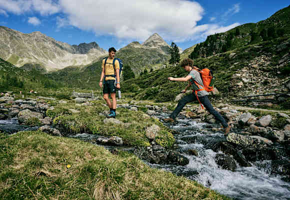 Person springt über Bergbach