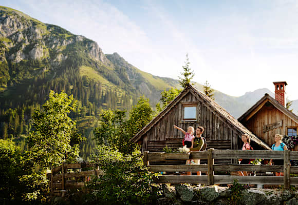 Eine Familie mit 2 Kindern steht auf einer Bergalm in der Steiermark im Sommer und beobachtet die Umgebung.