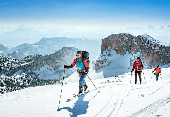 Sportler mit den Skiern am Weg zum Gipfel.