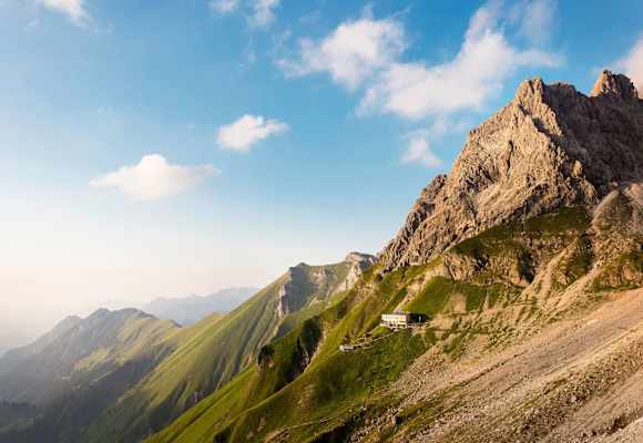 Das Waltenbergerhaus ist eingebettet in eine alpine Graslandschaft