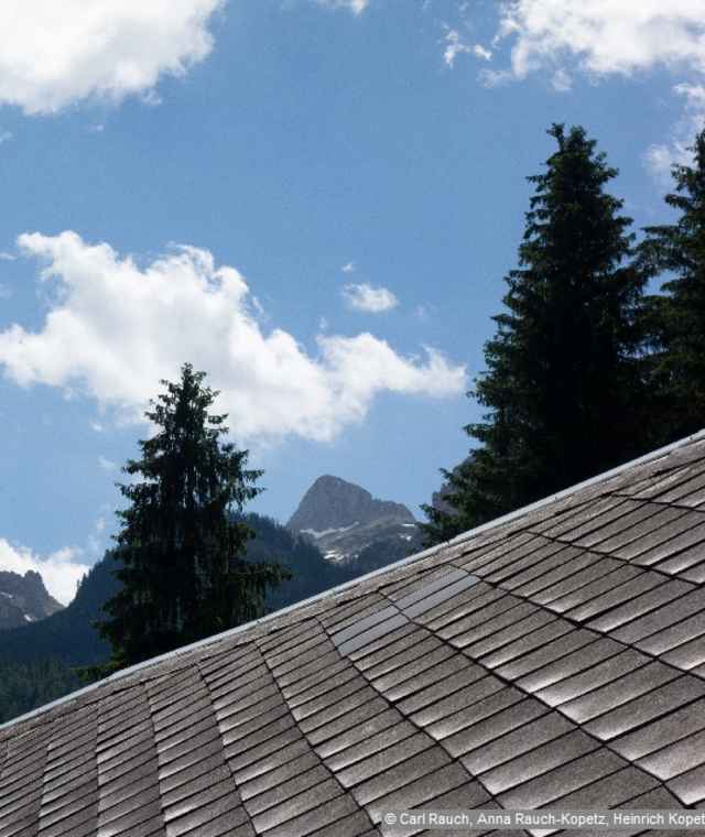 Dachlandschaft im Tal vor der Berglandschaft im Hintergrund.