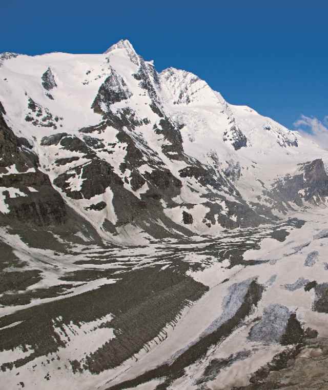 Was für ein Auftakt! Der Sprung ins Abenteuer Alpe-Adria-Trail könnte spektakulärer nicht sein: Schon die ersten Meter führen uns hinab zu den Ausläufern der Pasterze. Blickt man vom Ausgangspunkt ins Tal hinab, kann man die Ausmaße erahnen, die diese Eiszunge einmal hatte. Die Erderwärmung ließ den Gletscher in den letzten 150 Jahren beinahe auf die Hälfte seiner einstigen Größe zusammenschmelzen. 
